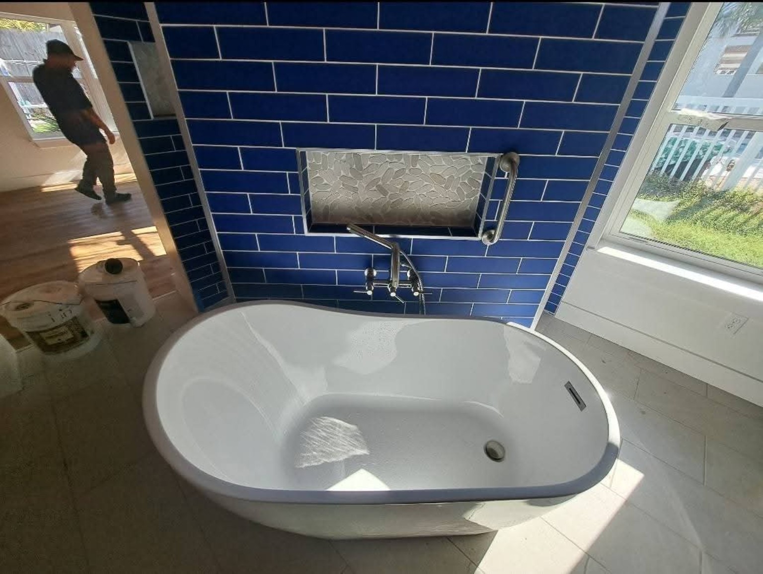 White freestanding bathtub with navy blue tiled feature wall