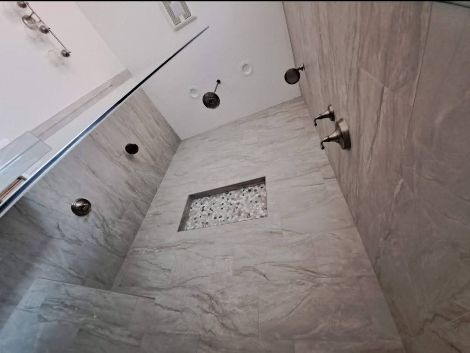 Large custom tiled shower with recessed niche and multiple fixtures
