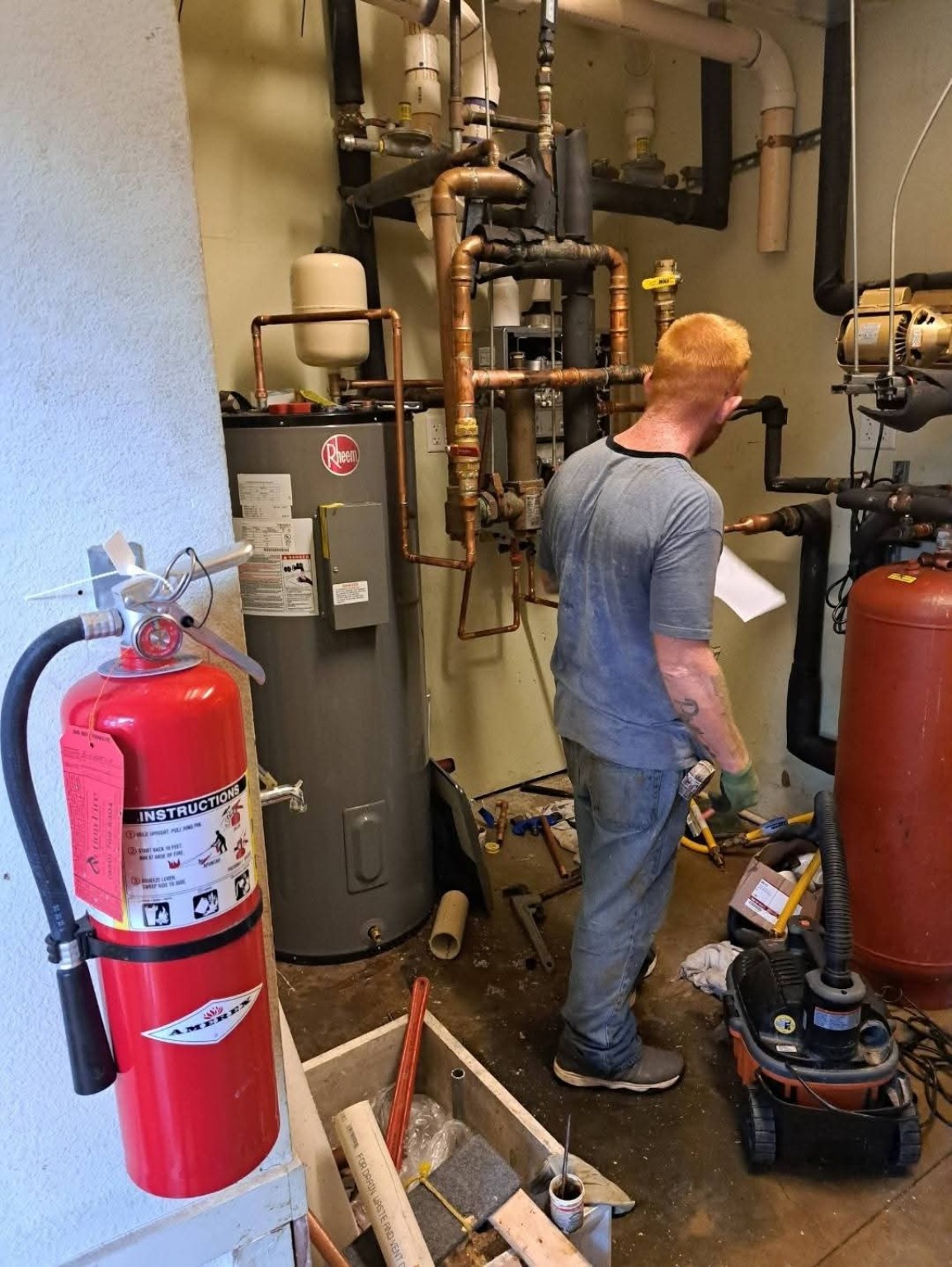Technician working on commercial water heater and copper piping